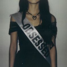 a woman in a black dress with a silver sash around her neck and the words boss on it