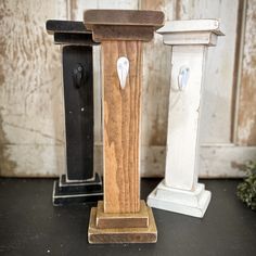 two wooden pedestals with white and black handles