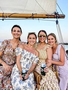 three women are sitting on a boat and posing for the camera while holding beer cans