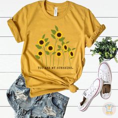 You are my sunshine T shirt, Sunflower T-shirt,Sunflower lover, Graphic Tee, Sunflower Tee,Inspirational Tee, Womens Floral Tee,Botanical Shirt,Garden shirt. This t-shirt is everything you've dreamed of and more. It feels soft and lightweight, with the right amount of stretch. It's comfortable and flattering for both men and women. * 100% combed and ring-spun cotton (Heather colors contain polyester) * Ash color is 99% combed and ring-spun cotton, 1% polyester * Heather colors are 52% combed and Cotton Crew Neck T-shirt With Sunflower Design, Yellow T-shirt With Sunflower Design For Spring, Crew Neck Cotton T-shirt With Sunflower Design, Yellow Short Sleeve T-shirt With Sunflower Design, Yellow Sunflower Print Graphic Tee, Cotton T-shirt With Sunflower Design, Trendy Relaxed Fit T-shirt With Sunflower Print, Summer Sunflower Design Short Sleeve T-shirt, Yellow Short Sleeve Tops With Sunflower Design