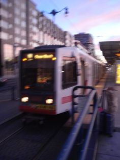 a white and red train traveling down tracks next to a loading platform with people standing on it