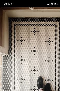 a person standing in front of a door with black and white tiles on the floor