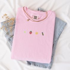 Welcome the sunny days with our Sunkissed Strawberry and Bee Embroidered T-Shirt! Made from 100% cotton Soft Comfort Colors, this shirt is both stylish and comfortable, perfect for your summer adventures.Features:Material: 100% cotton Soft Comfort ColorsSizes: S, M, L, XL, 2XL (refer to size chart in images)Colors Available: Banana, Bay, Blossom, Chalky Mint, Chambray, Ivory, Orchid, Peachy, Violet (Note: Colors may vary slightly due to monitor settings)Design: Summer-inspired embroidery featuring a daisy, strawberry, sun, and bee on the center chestCare Instructions: Machine wash cold, tumble dry lowThis Sunlissed Strawberry and Bee Embroidered T-Shirt is a delightful addition to your wardrobe, bringing a touch of sunshine wherever you go. Perfect for picnics, beach days, or casual outing Trendy Embroidered Summer T-shirt, Trendy Summer T-shirt With Embroidered Text, Trendy T-shirt With Embroidered Text For Summer, Pink Summer T-shirt For Everyday Wear, Pink Summer T-shirt For Everyday, Pink Summer Tops With Embroidered Graphics, Pink Embroidered Summer Top, Pink Embroidered Tops For Summer, Summer Relaxed Fit T-shirt With Embroidered Text