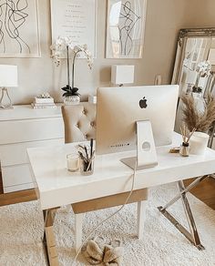 an apple computer sitting on top of a white desk next to a mirror and vase