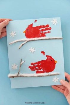 handprinted red birds on a branch with snowflakes and branches in the background