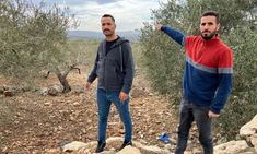 two men standing on rocks pointing at something