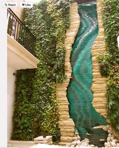 an artificial waterfall in the middle of a building with plants growing on it's sides