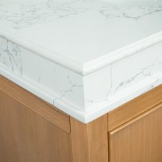 a white marble counter top sitting on top of a wooden cabinet