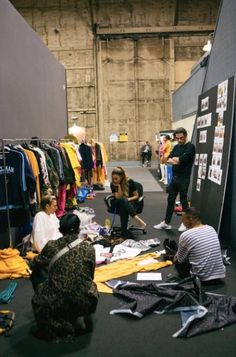 several people sitting on the floor looking at clothes