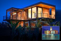 a modern house is lit up at night with lights on the windows and balconies