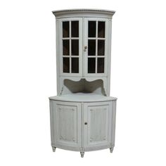 a white corner cabinet with glass doors on the top and bottom, against a white background