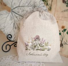 an embroidered bag sitting on top of a doily next to some flowers and leaves