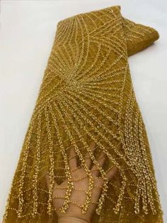 a woman's hand is covered with gold beaded mesh and beads on her arm