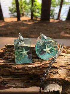 two sea glass pendants with starfish on them sitting on a piece of wood