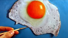 a person is painting an egg on a blue surface