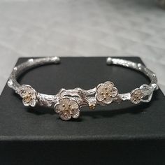 This Bracelet Is Absolutely Stunning. Has Four Little Flowers On It And The Band Looks Like A Branch. So Much Detail In This Little Bracelet! Brand New, Only Worn For The Photo. Little Bits Of Gold Tone In The Flowers. This Bracelet Is Very Sturdy Not Flimsy. Cuff/Bangle/Delicate/Petite/Danity/Unique Delicate Silver Flower Bracelets, Delicate Silver Flower Bracelet, Gold Flower-shaped Elegant Bracelets, Elegant Gold Flower-shaped Bracelets, Gold Flower-shaped Metal Bracelets, Gold Flower-shaped Cubic Zirconia Bracelets, Vintage Flower-shaped Metal Bracelets, Flower Bracelet, Little Flowers