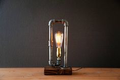 a lamp that is sitting on top of a wooden table next to a black wall