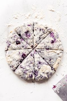 blueberry scones cut into eight pieces on a white surface with a knife next to them