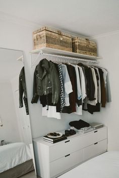 an organized closet with clothes and shoes hanging on the wall, along with a bed