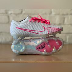 a pair of white and pink shoes sitting on top of a wooden table