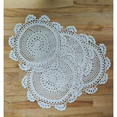 three white doily on a wooden floor with a black cat sitting next to it