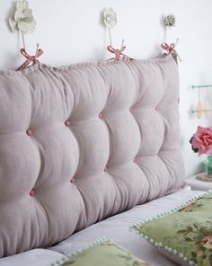 the headboard of a bed with pink buttons and bows on it's back