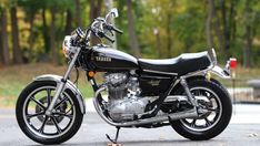 a black and silver motorcycle parked on the side of a road in front of trees