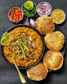 a black plate topped with bread and beans next to bowls of food on a table