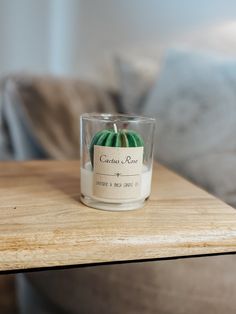 a small glass candle sitting on top of a wooden table next to a couch in a living room