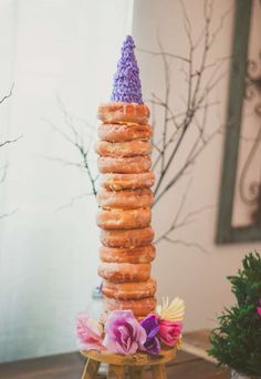 a stack of doughnuts sitting on top of a wooden table next to flowers