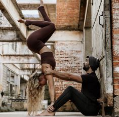 a man and woman are doing acrobatic tricks on the ground in an alleyway