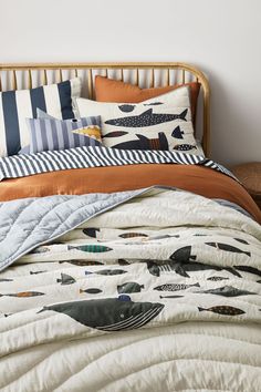 a bed with an orange and white comforter on top of it next to a wooden headboard