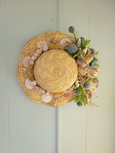 a straw hat with seashells and flowers is hanging on the wall next to a door