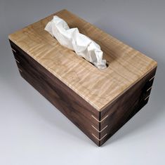 a tissue dispenser sitting on top of a wooden box with paper in it