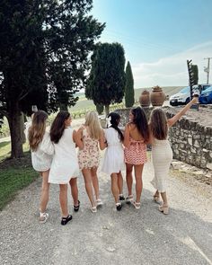 four girls are standing in the middle of a road and one girl is holding her arms up