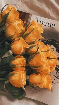 a bouquet of yellow roses sitting on top of a magazine