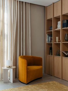 an orange chair sitting in front of a book shelf