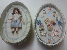 two tins with dolls in them sitting on a table