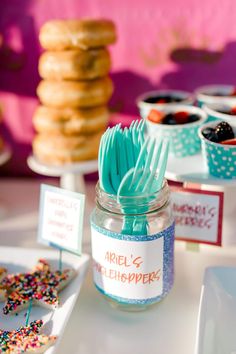 there are many desserts in the jars on the table with blue strawberries and sprinkles