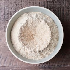 a white bowl filled with flour on top of a wooden table