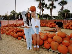 two young women standing in front of pumpkins