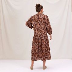 Add a splash of joy to your wardrobe with the Black Spice Madine Drop Waist Maxi Dress! Crafted from 100% cotton, this dress offers a delightfully comfortable fit that drapes beautifully. The vibrant pattern in warm spice tones is both eye-catching and stylish, perfect for making a statement. The full-length sleeves with elastic cuffs add a touch of charm and practicality, while the V-neck mandarin collar gives it an elegant touch. The dress features playful details like long decorative tassels Flowy Cotton Maxi Dress For Fall, Cotton Maxi Dress For Fall Beach Outings, Cotton Maxi Dress For Fall Beach, Cotton Maxi Dress For Beach In Fall, Relaxed Fit Cotton Midi Dress With Floral Print, Relaxed Fit Cotton Maxi Dress For Fall, Brown Cotton Midi Dress For Beach, Brown Relaxed Fit Cotton Dress, Fall Floral Print Orange Maxi Dress