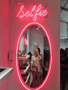 a woman standing in front of a mirror with the word selfie on it's side