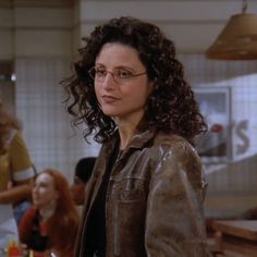 a woman with glasses standing in front of a counter