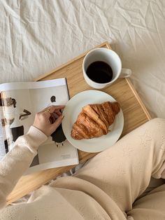 a person is reading a book and eating croissant