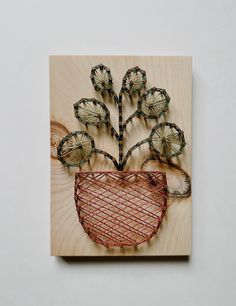 a piece of wood with wire work on it and flowers in the shape of a heart