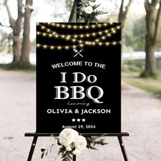 a welcome sign with lights and flowers on it for a wedding or anniversary party in the woods