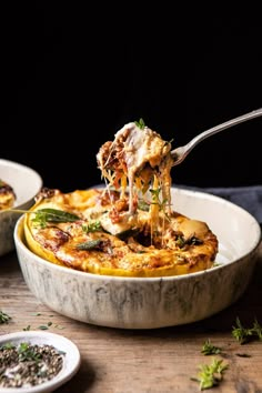 a spoonful of pasta being lifted from a casserole dish on a wooden table