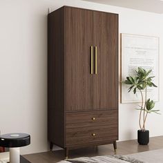 a brown armoire sitting next to a plant on top of a wooden table in front of a white wall