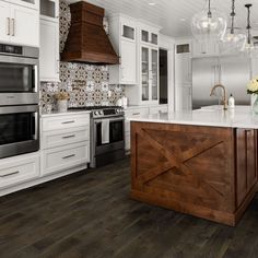 a large kitchen with white cabinets and wood flooring on the countertops, along with an island in the middle